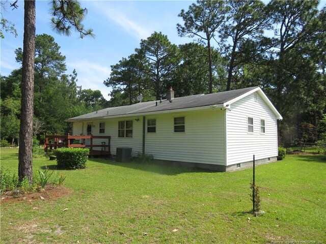 rear view of house with cooling unit, a lawn, and a deck