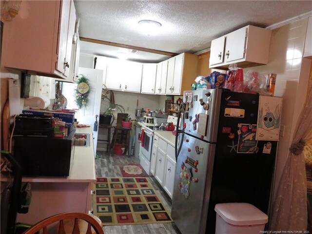 kitchen with stainless steel fridge, white cabinets, a textured ceiling, and electric stove