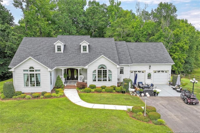 cape cod-style house featuring a front lawn, a porch, and a garage