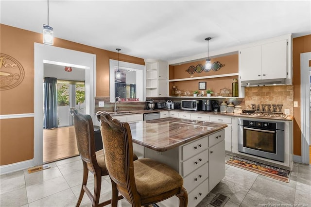 kitchen with a center island, white cabinets, pendant lighting, and appliances with stainless steel finishes