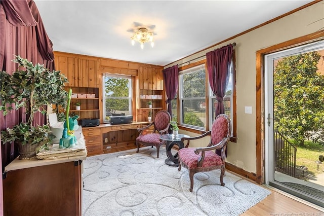 sitting room with light hardwood / wood-style flooring, ornamental molding, and wood walls