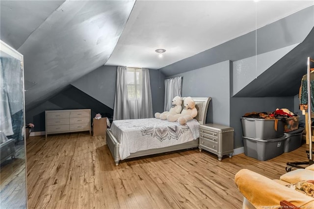 bedroom with light wood-type flooring and vaulted ceiling