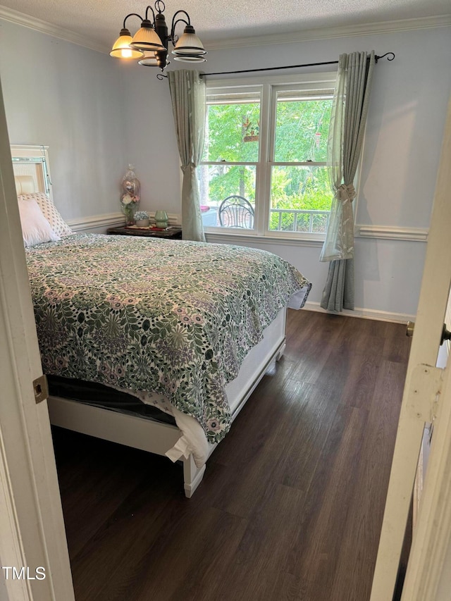 bedroom featuring dark hardwood / wood-style floors, ornamental molding, an inviting chandelier, and a textured ceiling