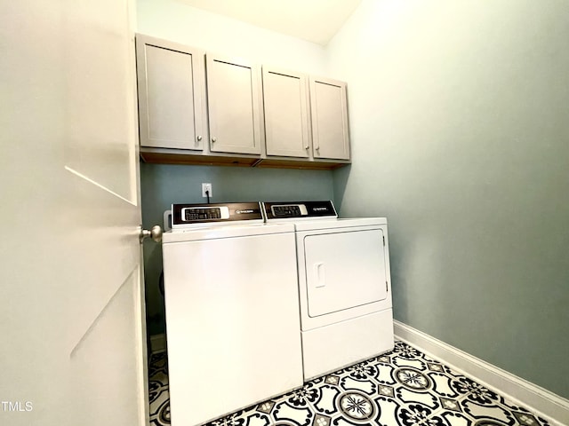 clothes washing area featuring washing machine and dryer, light tile patterned floors, and cabinets