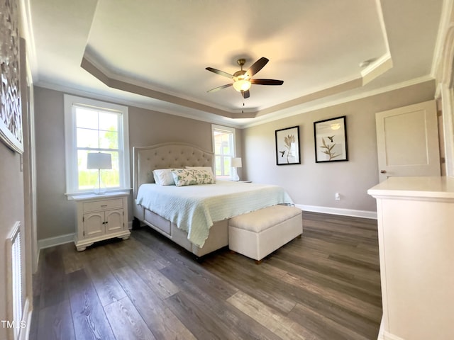 bedroom with dark hardwood / wood-style flooring, a tray ceiling, ceiling fan, and ornamental molding