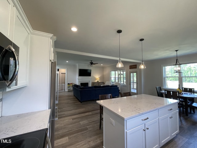 kitchen with white cabinetry, light stone countertops, dark wood-type flooring, a kitchen island, and ceiling fan with notable chandelier