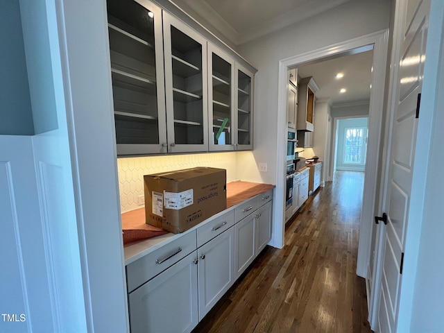 bar featuring dark wood-type flooring, wooden counters, backsplash, ornamental molding, and white cabinets