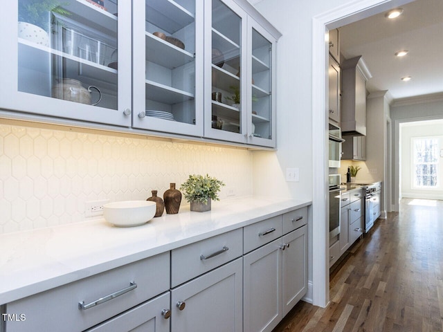 bar with dark wood-style floors, recessed lighting, decorative backsplash, ornamental molding, and oven