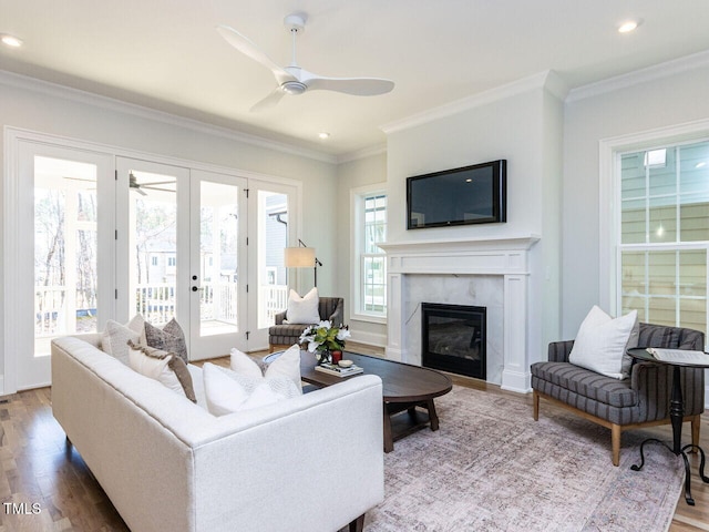 living area with a high end fireplace, ceiling fan, wood finished floors, crown molding, and recessed lighting