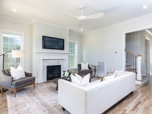 living area featuring light wood finished floors, visible vents, stairway, and a high end fireplace