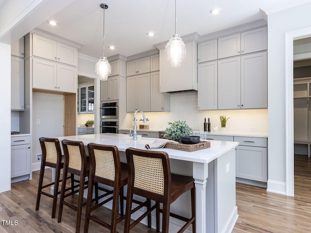 kitchen featuring decorative backsplash, light wood-style flooring, gray cabinets, and light countertops