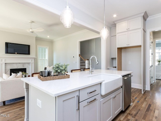 kitchen with dishwasher, open floor plan, crown molding, a sink, and a high end fireplace