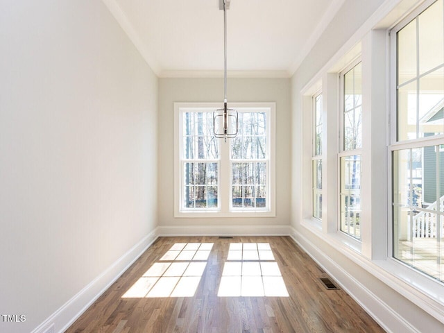 unfurnished dining area featuring visible vents, wood finished floors, baseboards, and ornamental molding