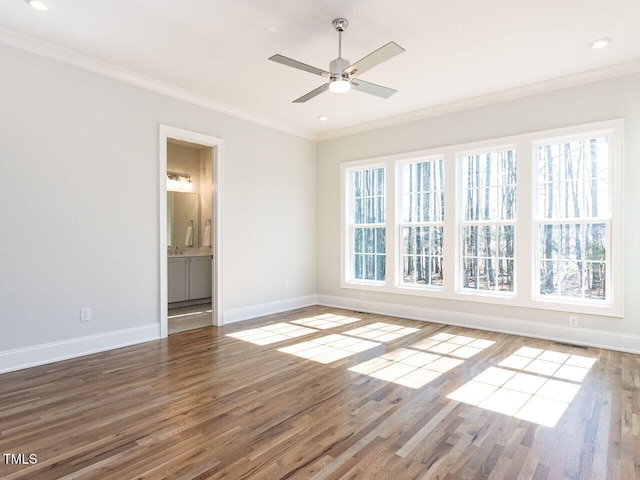 spare room with a ceiling fan, visible vents, wood finished floors, baseboards, and ornamental molding