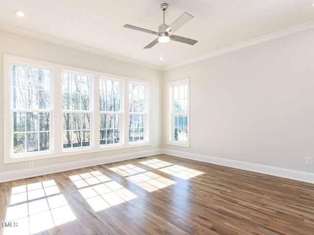 empty room with wood finished floors, baseboards, and ornamental molding