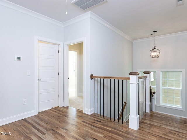 hallway with crown molding, visible vents, wood finished floors, and an upstairs landing