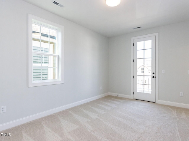 spare room featuring visible vents, baseboards, and light colored carpet