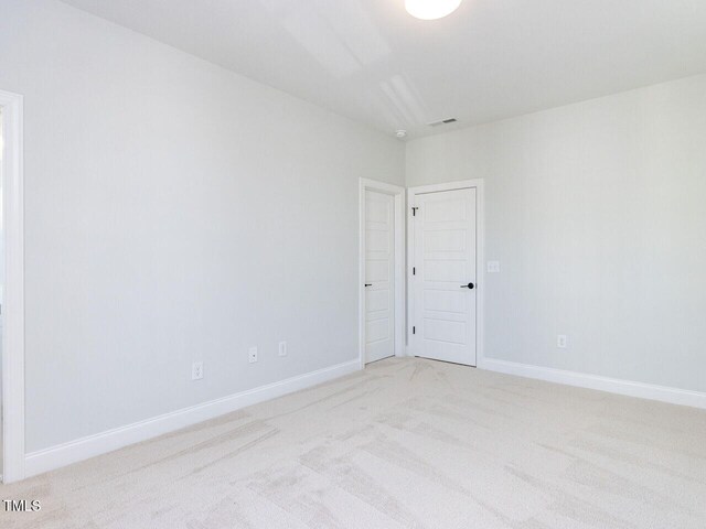 spare room featuring visible vents, baseboards, and light colored carpet