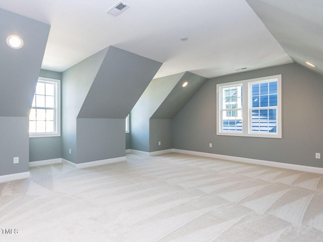 bonus room with vaulted ceiling, baseboards, visible vents, and light carpet