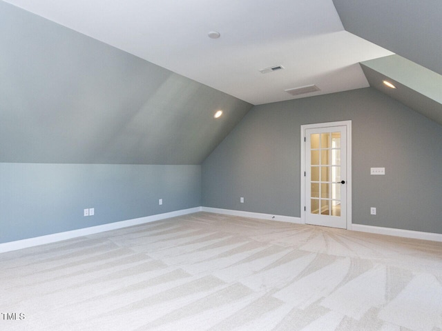 bonus room featuring vaulted ceiling, light carpet, visible vents, and baseboards