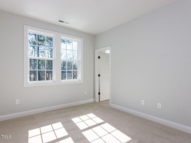 empty room with light colored carpet, visible vents, and baseboards