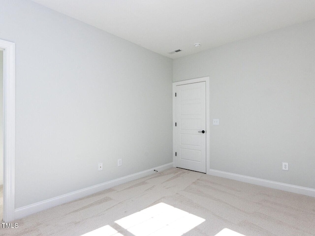 spare room with visible vents, baseboards, and light colored carpet