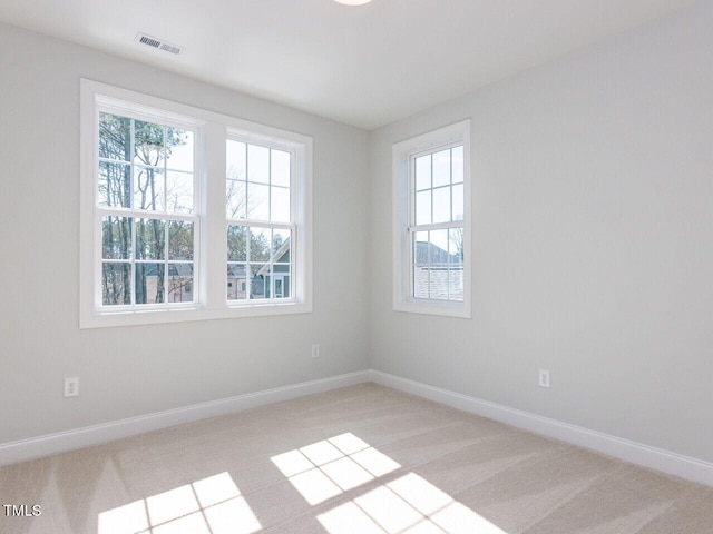 spare room with baseboards, visible vents, and light carpet