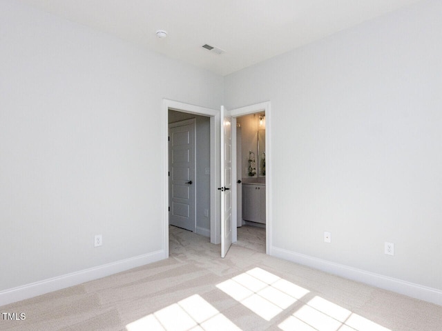 unfurnished bedroom featuring visible vents, light colored carpet, connected bathroom, and baseboards