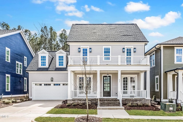 view of front of property featuring covered porch, driveway, an attached garage, and a balcony