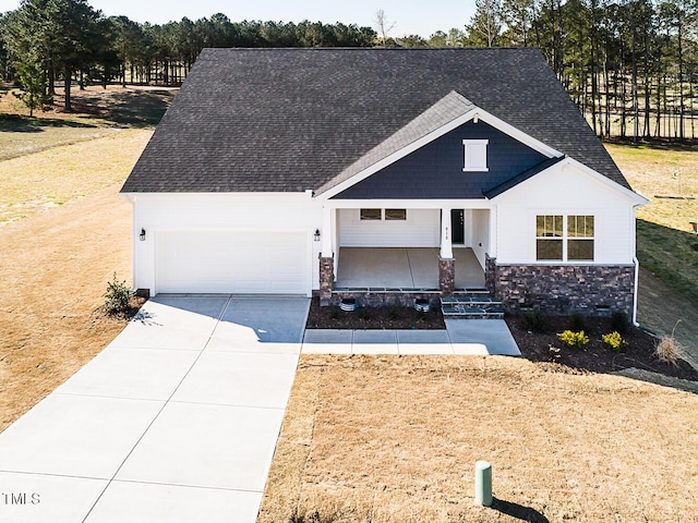 view of front of property with stone siding, driveway, roof with shingles, and an attached garage