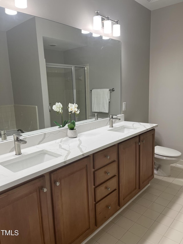 bathroom featuring tile patterned flooring, vanity, toilet, and a shower with shower door