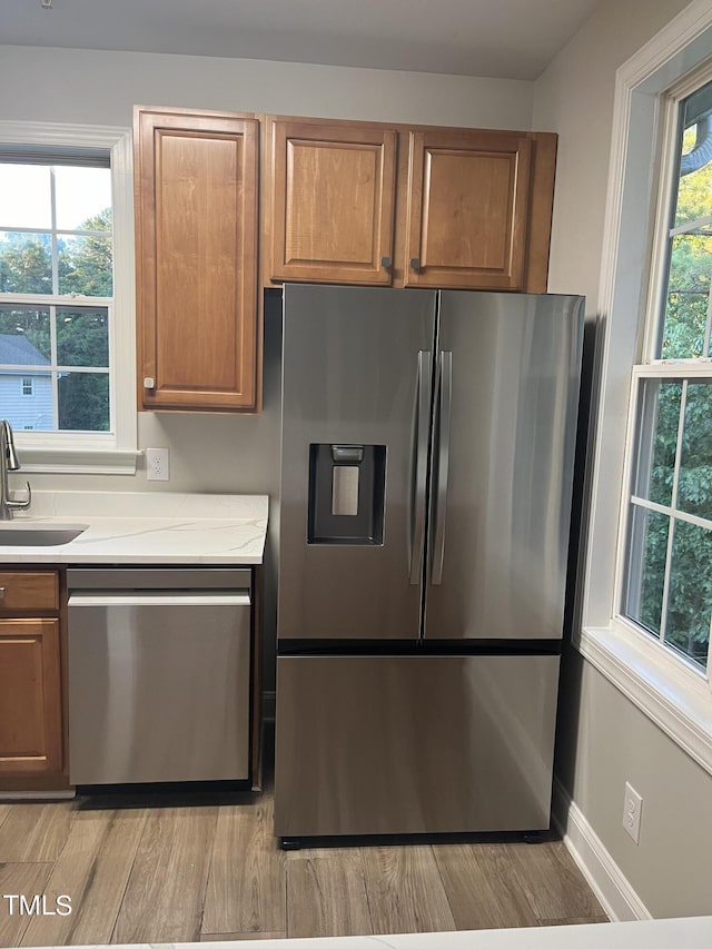 kitchen featuring stainless steel appliances, plenty of natural light, light hardwood / wood-style floors, and sink