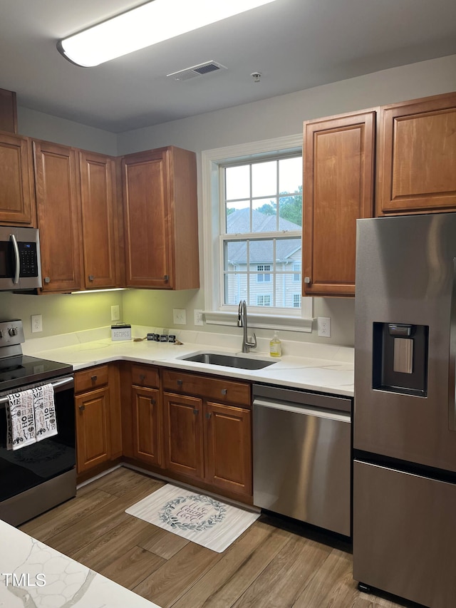 kitchen with appliances with stainless steel finishes, light hardwood / wood-style floors, and sink