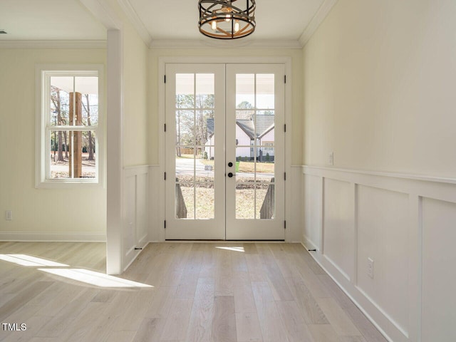 doorway to outside with a notable chandelier, light hardwood / wood-style flooring, french doors, and crown molding