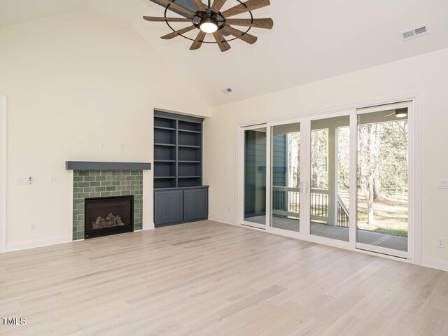 unfurnished living room featuring high vaulted ceiling, a brick fireplace, light wood-type flooring, and ceiling fan