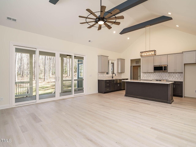 kitchen with ceiling fan, decorative backsplash, gray cabinets, a kitchen island, and pendant lighting