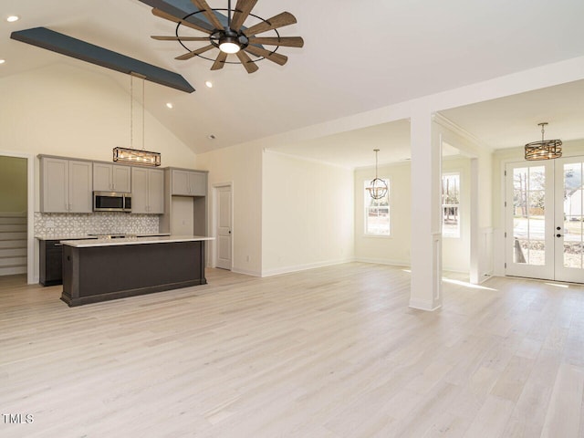 kitchen featuring a center island, french doors, ceiling fan with notable chandelier, decorative backsplash, and beam ceiling