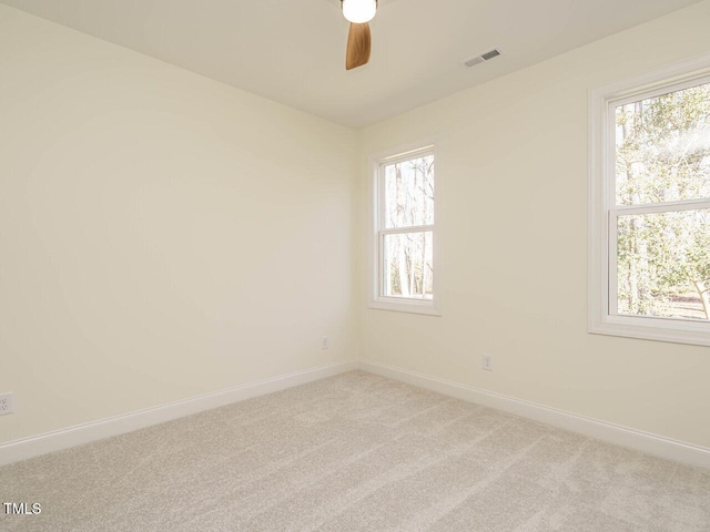 carpeted spare room featuring ceiling fan and a wealth of natural light