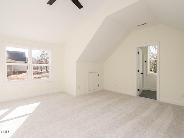 additional living space with a healthy amount of sunlight, light colored carpet, vaulted ceiling, and ceiling fan