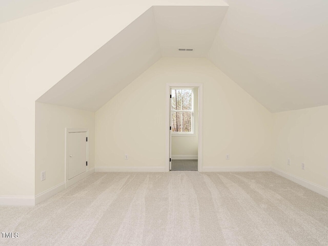 additional living space featuring light colored carpet and vaulted ceiling