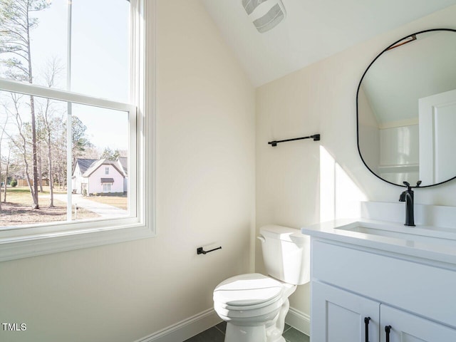 bathroom featuring vaulted ceiling, a wealth of natural light, vanity, and toilet