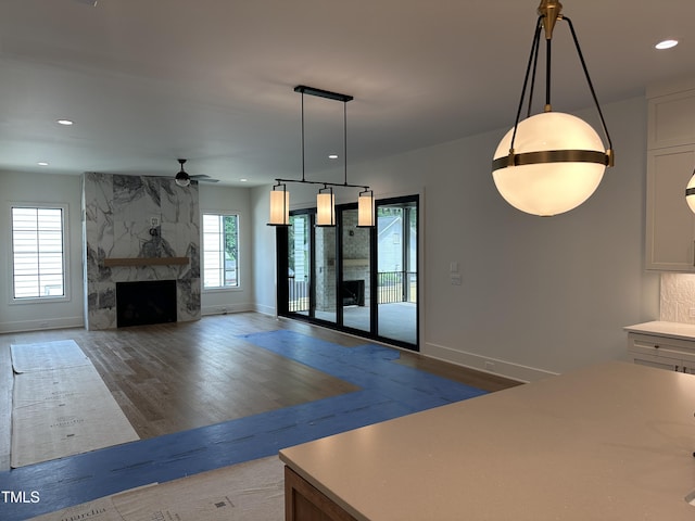 unfurnished living room with recessed lighting, wood finished floors, a ceiling fan, baseboards, and a large fireplace