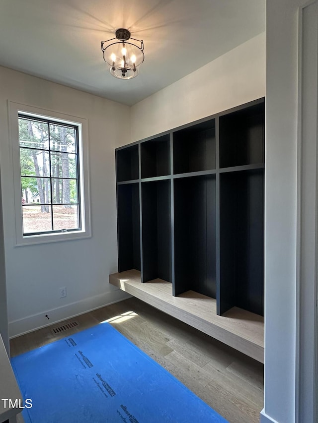 mudroom featuring an inviting chandelier, wood finished floors, visible vents, and baseboards