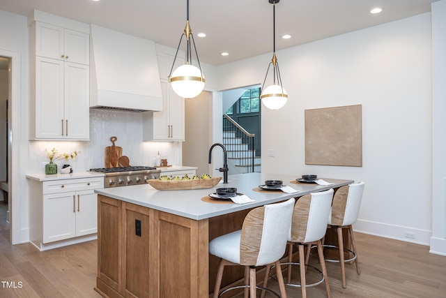 1000 Marilyn Dr, Raleigh, NC 27607 - kitchen featuring custom range hood, light wood-type flooring, a center island with sink, recessed lighting, and white cabinets