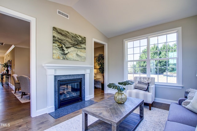 living room featuring wood finished floors, baseboards, visible vents, a premium fireplace, and vaulted ceiling