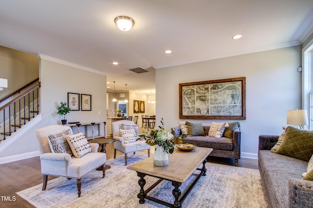 living area with baseboards, visible vents, wood finished floors, and ornamental molding