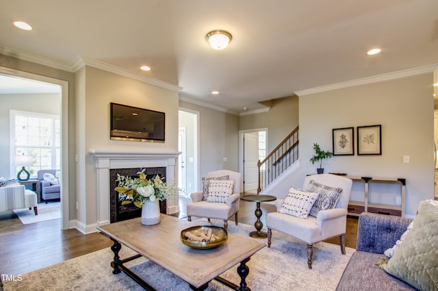 living area with crown molding, stairs, wood finished floors, recessed lighting, and a high end fireplace