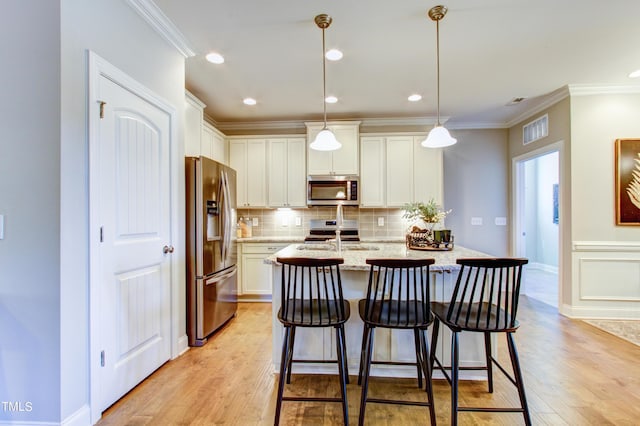 kitchen with visible vents, white cabinets, appliances with stainless steel finishes, and hanging light fixtures