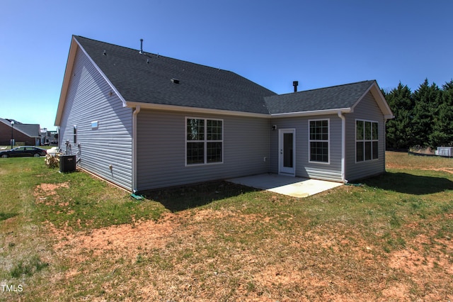 rear view of house with central AC unit, a shingled roof, a patio area, and a yard