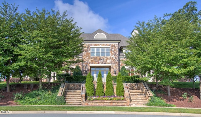 view of front of home with stairs, stone siding, and french doors